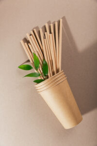 Disposable paper tableware. Cups and straws on beige background. Plastic free and zero waste concept.